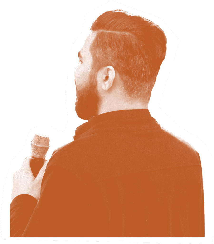 Young man with a beard standing holding a microphone and speaking